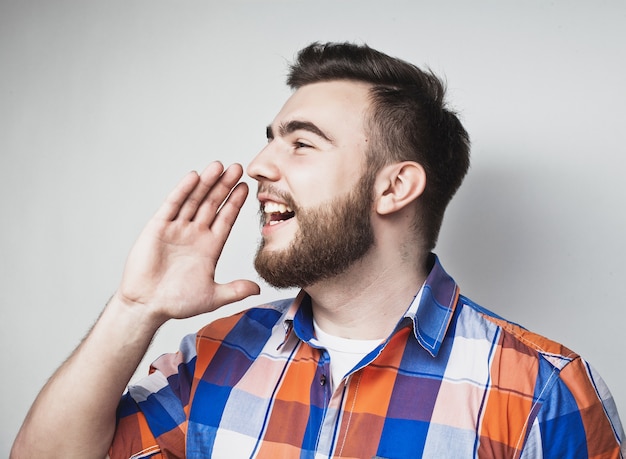 Concept de style de vie et de personnes : Portrait d'un beau jeune homme criant, sur fond gris