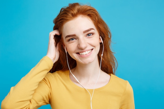 Concept de style de vie - Portrait de joyeux joyeux gingembre cheveux roux, vous aimez écouter de la musique avec un casque joyeux souriant à la caméra. Isolé sur fond bleu Pastel. Espace de copie.