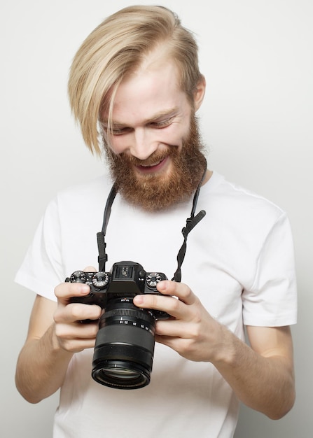 Concept de style de vie, de technologie et de personnes : photographe professionnel. Portrait of young man in shirt holding camera sur fond blanc