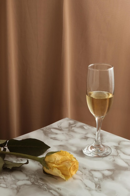 Concept de style vintage avec verre à vin et fleur rose jaune sur table en marbre Esthétique moderne