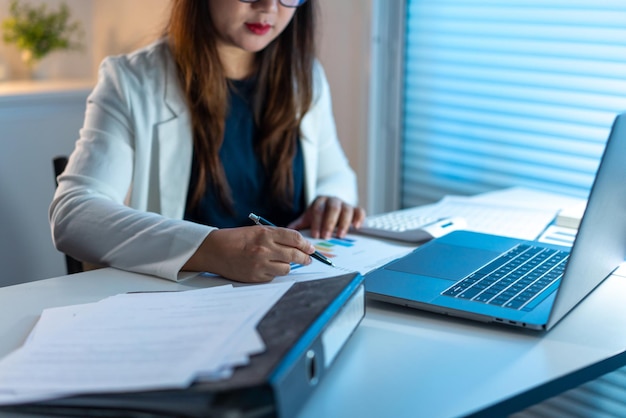 Concept de surmenage La femme qui travaille assise à son bureau et écrit son travail sur le papier