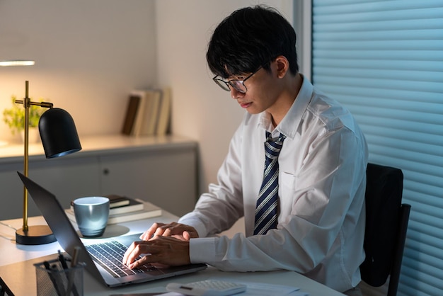 Concept de surmenage L'homme assis à son bureau et se concentrant sur son ordinateur portable.