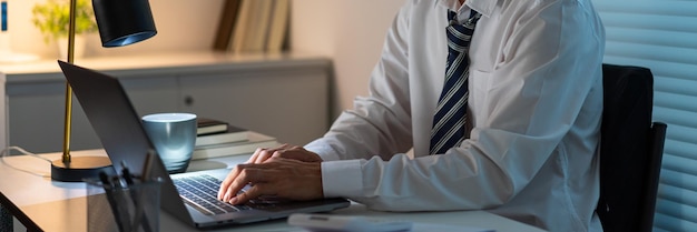 Concept de surmenage L'homme assis à son bureau et se concentrant sur le travail à travers son ordinateur portable