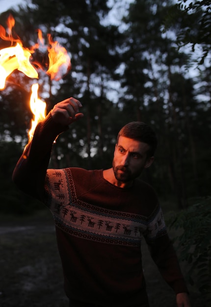 Concept surréaliste - un homme avec une main brûlante illumine l'espace autour de lui dans la forêt.