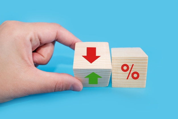 Concept de taux d'intérêt financiers et hypothécaires. La main change les flèches sur le cube de haut en bas