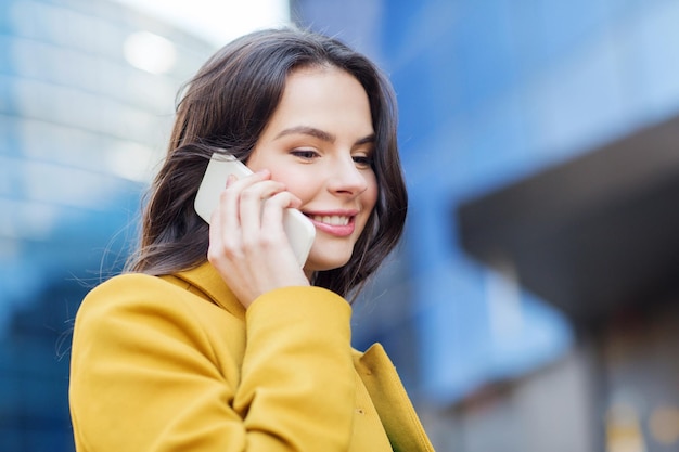 concept de technologie, de communication et de personnes - jeune femme ou fille souriante appelant sur un smartphone dans la rue de la ville