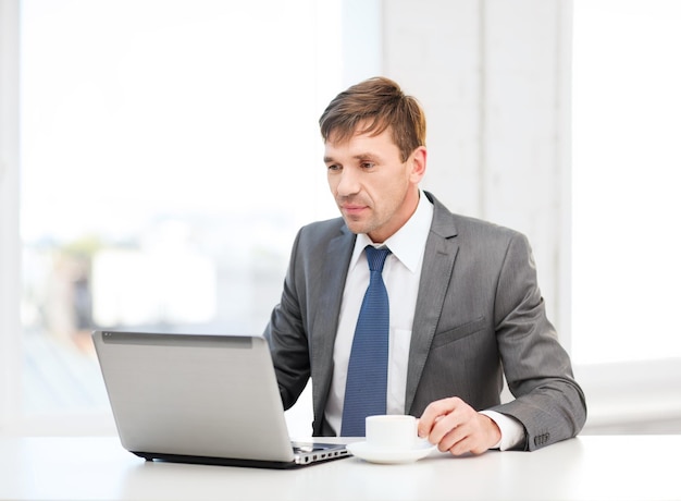 concept de technologie, d'entreprise et de bureau - bel homme d'affaires travaillant avec un ordinateur portable