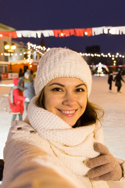 Concept de technologie et de loisirs d'hiver de Noël jeune femme heureuse prenant la photo avec le smartphone dessus