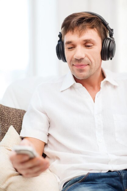 concept de technologie, de loisirs et de style de vie - homme heureux avec des écouteurs écoutant de la musique à la maison