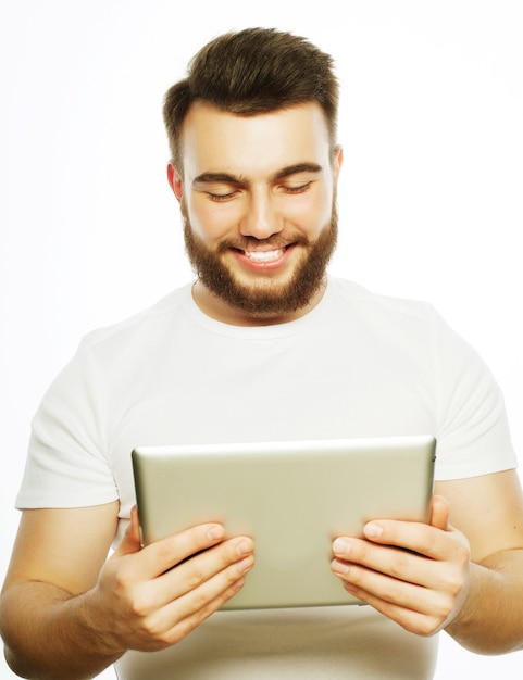 Concept de technologie et de mode de vie : jeune homme portant un t-shirt blanc à l'aide d'un ordinateur tablette - isolé sur fond blanc