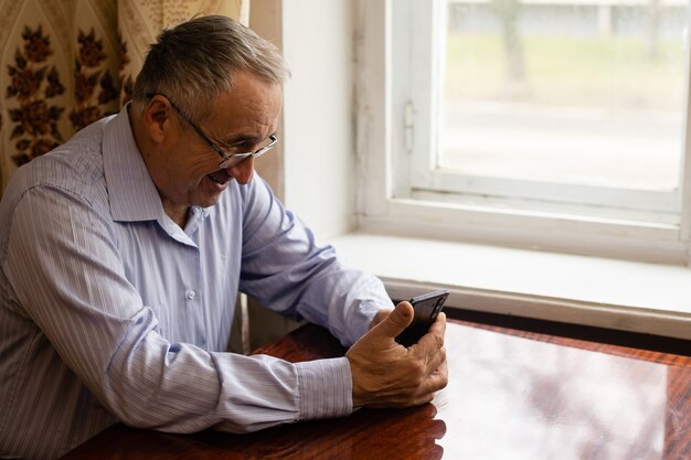 concept de technologie, de personnes, de mode de vie et de communication - homme âgé heureux composant un numéro de téléphone et envoyant des SMS sur un smartphone à la maison