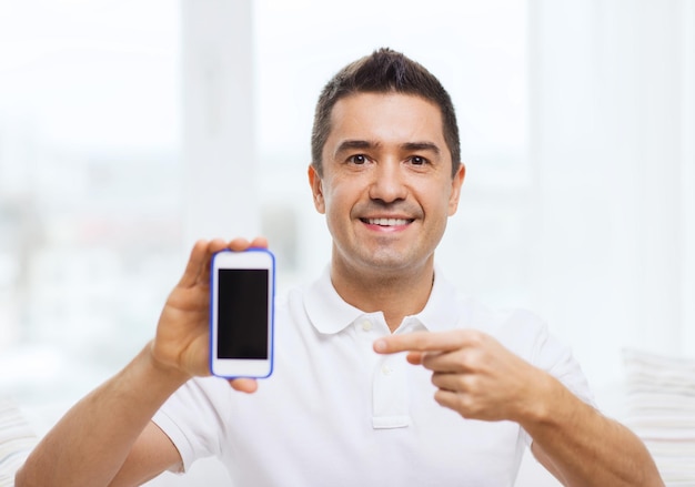 Photo concept de technologie, de personnes, de style de vie et de communication - homme heureux montrant un écran blanc noir de smartphone à la maison