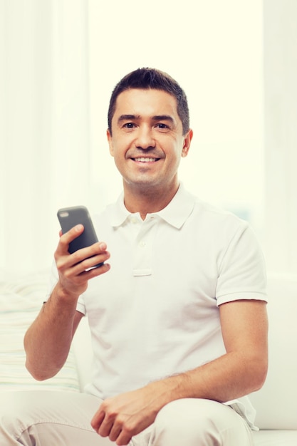 concept de technologie, de personnes, de style de vie et de communication - homme heureux avec smartphone à la maison