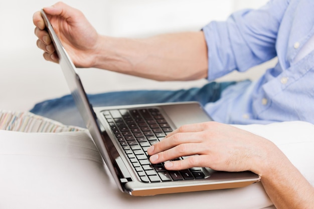 concept de technologie, de personnes et de style de vie - gros plan de mains masculines tapant sur le clavier d'un ordinateur portable à la maison