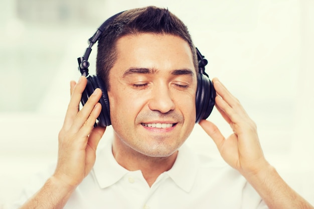 concept de technologie, de personnes et de style de vie - homme heureux dans des écouteurs écoutant de la musique à la maison