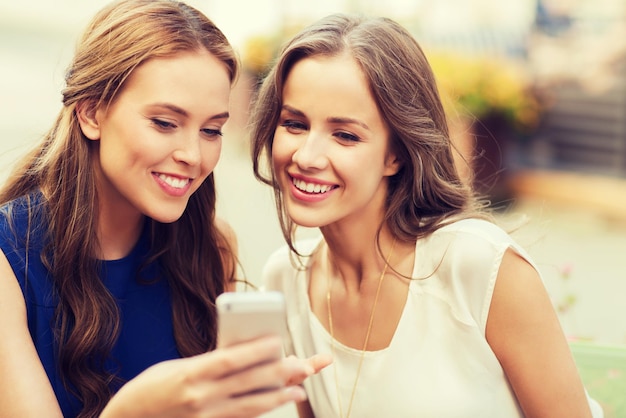 concept de technologie, de style de vie, d'amitié et de personnes - jeunes femmes ou adolescentes heureuses avec smartphone au café en plein air