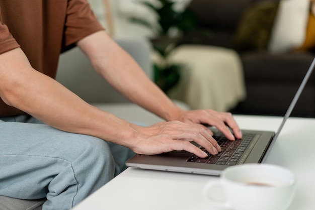 Concept technologique L'homme en T-shirt marron se concentrant sur la saisie de quelque chose sur son ordinateur portable