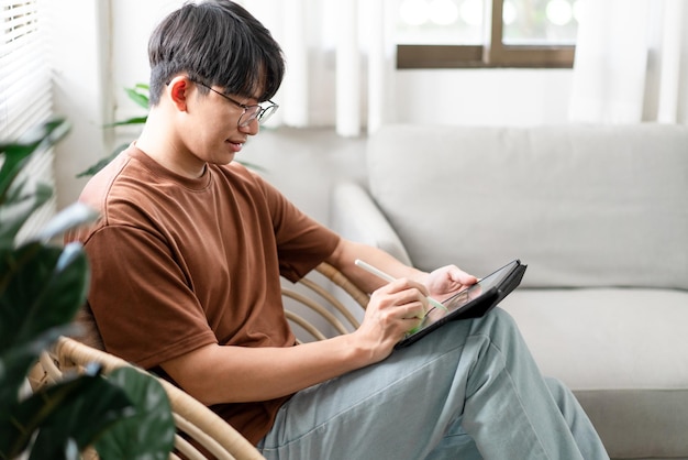 Concept technologique Le jeune homme qui est assis sur la chaise tenant son iPad