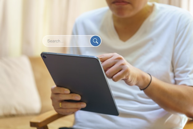 Photo concept technologique. main de l'homme tenant et utilisant une tablette d'ordinateur avec l'icône de boîte de barre de recherche.
