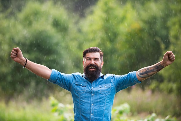 Concept de temps pluvieux orageux. Vêtements imperméables. Homme heureux sous la pluie. Ambiance d'automne.