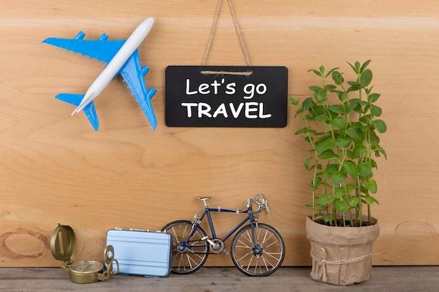 Concept de temps de voyage tableau noir avec texte Allons voyager modèle d'avion petit vélo et valise