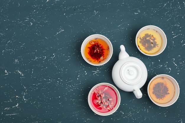 Concept de thé. Différentes sortes de thé sec dans des bols en céramique et des tasses de thé aromatique