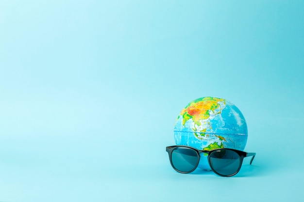 Concept de tourisme, écologie, vacances et globalisme. Globe en lunettes de soleil sur une bannière de fond bleu. Création minimale