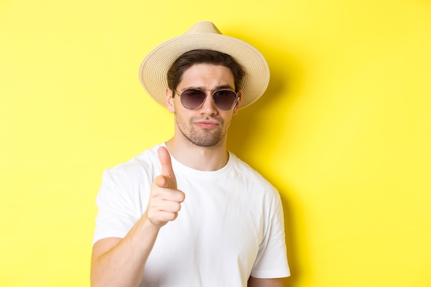 Concept de tourisme et de vacances en gros plan d'un gars cool en chapeau d'été et lunettes de soleil pointant le doigt sur ...