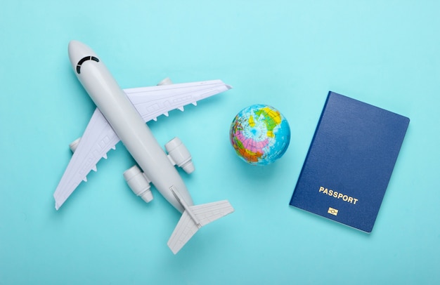 Concept de tourisme et de voyage. Globe, passeport, figurine d'avion de passagers sur le mur pastel bleu Vue de dessus. Mise à plat