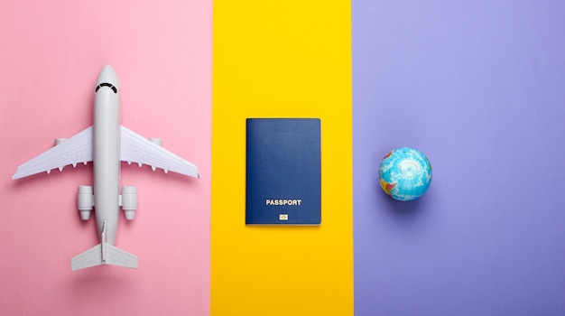 Concept de tourisme et de voyage. Émigration. Globe, passeport et avion de passagers sur le mur coloré Vue de dessus. Mise à plat