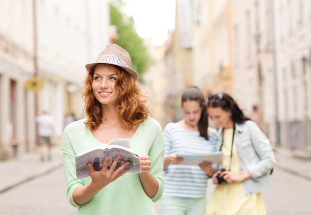 concept de tourisme, de voyage, de vacances et d'amitié - adolescentes souriantes avec guide de la ville, carte et appareil photo à l'extérieur