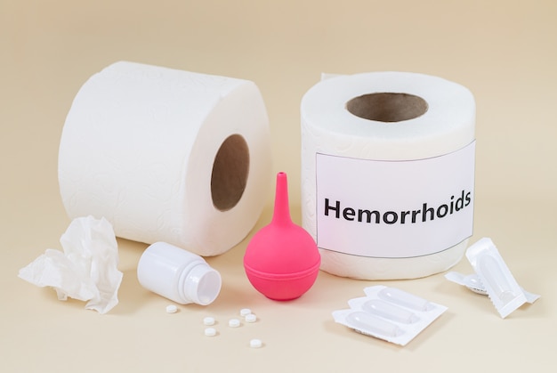 Concept de traitement des hémorroïdes et de la constipation. Rouleaux de papier toilette, suppositoires médicaux, pilules, lavement