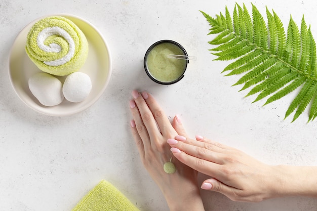 Concept de traitement spa beauté bien-être. femme enduit un gommage sur le bras. mur de béton blanc. vue de dessus. copie espace