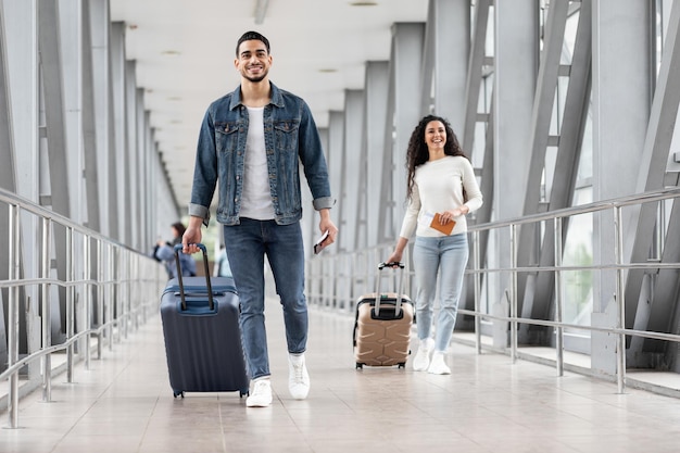 Concept de transport souriant homme et femme arabe avec des valises marchant à l'aéroport