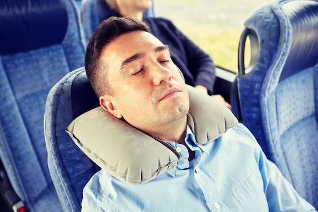 Photo concept de transport, de tourisme, de repos, de confort et de personnes - homme dormant dans un bus de voyage ou un train avec un oreiller gonflable pour le cou cervical