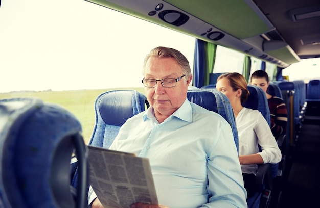 Photo concept de transport, de tourisme, de voyage et de personnes - homme senior lisant un journal dans un bus de voyage