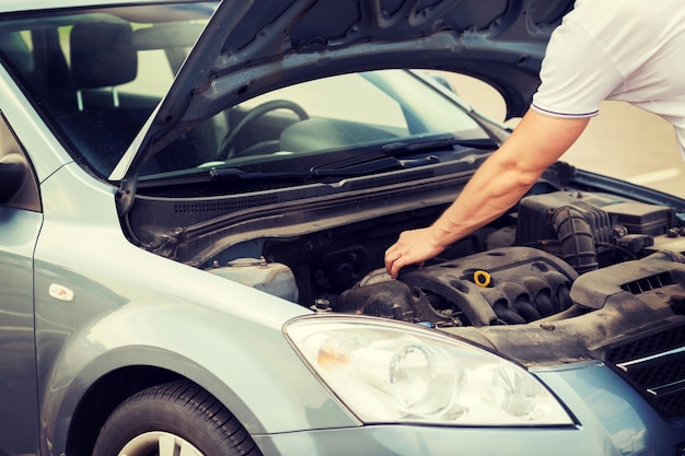 Photo concept de transport et de véhicule - homme ouvrant le capot de la voiture et regardant sous le capot