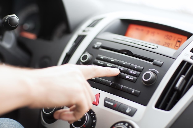 concept de transport et de véhicule - homme utilisant un système stéréo audio de voiture