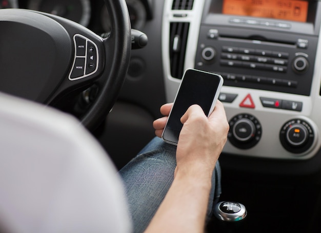 concept de transport et de véhicule - homme utilisant un téléphone en conduisant la voiture