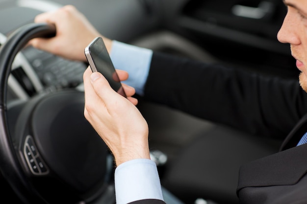 concept de transport et de véhicule - homme utilisant un téléphone en conduisant la voiture