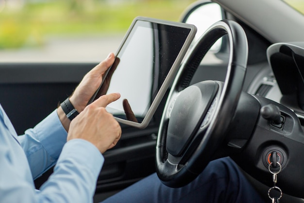 concept de transport, de voyage d'affaires, de technologie et de personnes - gros plan d'un jeune homme avec un ordinateur tablette au volant d'une voiture