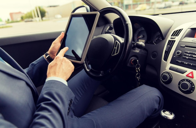 concept de transport, de voyage d'affaires, de technologie et de personnes - gros plan d'un jeune homme avec un ordinateur tablette au volant d'une voiture