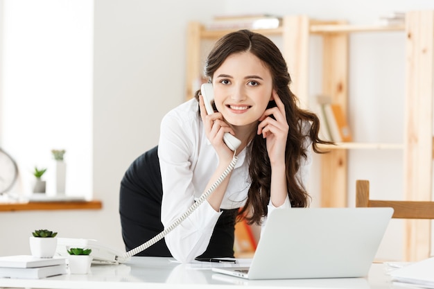 Concept de travail à domicile - Belle jeune femme dans sa maison travaillant sur ordinateur portable. Travailler à la maison.