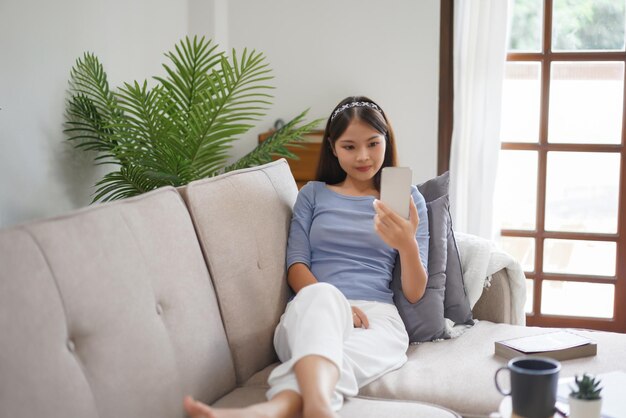 Concept de travail à domicile Les femmes d'affaires regardent un film sur un smartphone en position allongée sur le canapé