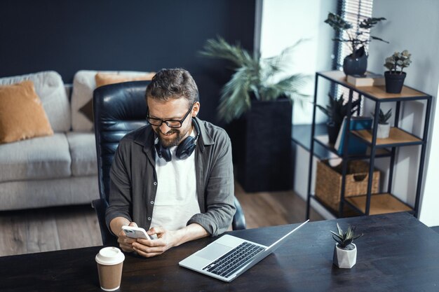 Concept de travail à domicile mettant en vedette un homme d'âge moyen travaillant sur un ordinateur portable Homme vu dans un environnement de bureau à domicile confortable mettant en évidence la commodité et les avantages de travailler dans le confort de son propre espace