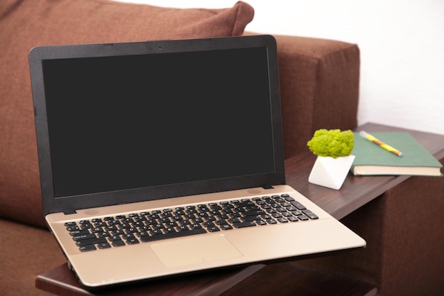 Concept de travail à domicile : ordinateur portable avec écran blanc vierge sur canapé-lit gris