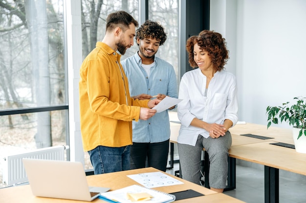 Concept de travail d'équipe Un groupe d'employés motivés de l'entreprise de différentes nationalités travaillent ensemble sur un nouveau projet dans un bureau moderne en discutant d'idées et d'objectifs.