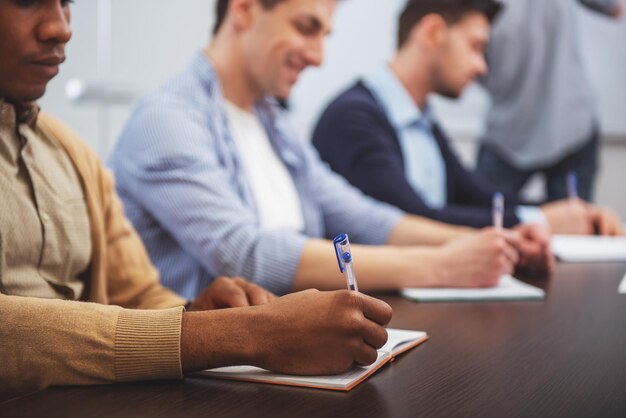 Concept de travail d'équipe Les jeunes sont assis sur la table et écrivent