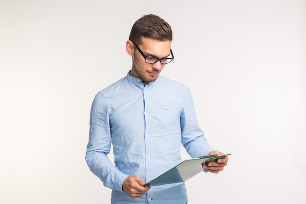 Concept de travail et de personnes - beau jeune homme dans des verres en regardant sur des notes sur le blanc