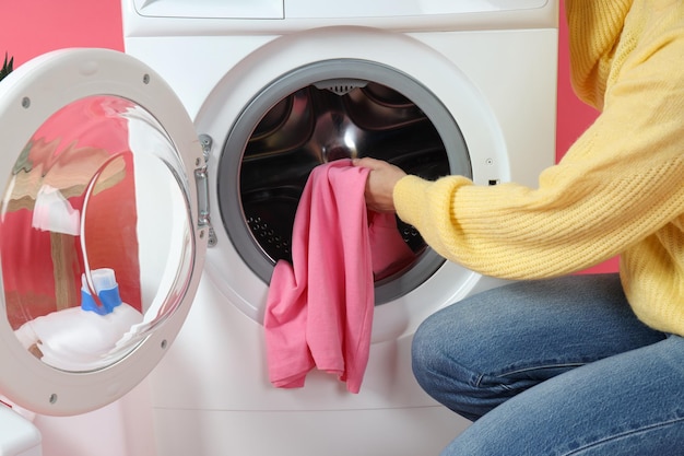 Concept de travaux ménagers avec machine à laver et fille sur fond rose